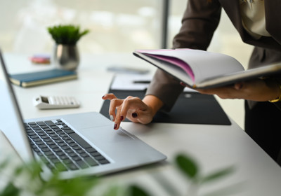 Unrecognizable Businesswoman Holding Notebook And Typing